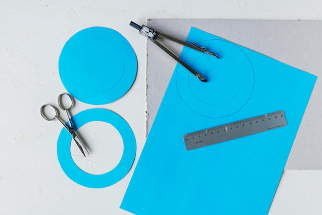 Blaues Papier mit Zirkel, Schere und Massstab